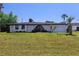 Inviting single-story home featuring a manicured lawn, lush landscaping, and charming front entrance at 20295 Lorenzo Ave, Port Charlotte, FL 33952