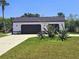 View of detached two-car garage with black doors, fresh landscaping, and spacious driveway at 20295 Lorenzo Ave, Port Charlotte, FL 33952