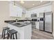Eat-in kitchen features white cabinets, stainless steel appliances, dark countertops, and sleek wood-look flooring at 215 S Westland Ave # 3, Tampa, FL 33606