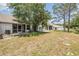 A view of the home's backyard with a grassy lawn, trees, and exterior structures at 2355 Bentley Dr, Palm Harbor, FL 34684