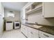 Spacious laundry room features a sink, granite counters, white cabinetry, washer, dryer, and tiled floors at 3109 W Granada St, Tampa, FL 33629