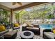 Enclosed patio with wicker seating, brick floors, a fire pit, and lush, tropical landscaping at 3109 W Granada St, Tampa, FL 33629