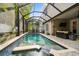Enclosed pool features a mosaic tile trim, surrounding patio, lush greenery, and ample sunlight at 3109 W Granada St, Tampa, FL 33629