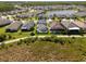 Aerial view of homes with screened-in pools and lush landscaping in a residential neighborhood by a pond at 3161 Satilla Loop, Odessa, FL 33556