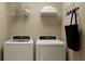 Practical laundry room with modern washer and dryer units and convenient shelving at 36075 Risa Michele St, Zephyrhills, FL 33541