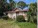 Inviting single-story home with secure metal door, framed windows, and a lush garden with mature tropical landscaping at 3706 N 36Th St, Tampa, FL 33610