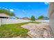 View of a yard with lush grass, a tree, stone pavers, and surrounded by white fences at 3927 Spence Ave, Tampa, FL 33614