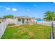 Quaint single-story house featuring a grassy front yard, blue door, and charming, fenced outdoor seating at 3927 Spence Ave, Tampa, FL 33614