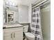Well-lit bathroom featuring a granite countertop vanity and shower with gray and white striped curtain at 39650 Us Highway 19 N # 143, Tarpon Springs, FL 34689