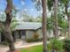 Charming single-story home featuring a beautifully landscaped front yard with mature trees and a welcoming walkway at 39650 Us Highway 19 N # 143, Tarpon Springs, FL 34689