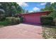 Garage with a two-car garage door and mature landscaping at 4388 Tiffin Ave, Spring Hill, FL 34609
