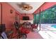 Covered outdoor patio with a ceiling fan, table, seating and access to the screened-in pool at 4388 Tiffin Ave, Spring Hill, FL 34609