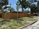 View of a corner lot featuring a wooden fence, grass, and shade trees on a sunny day at 440 53Rd N St, St Petersburg, FL 33710