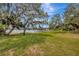 Expansive backyard with lush green lawn and mature trees overlooking the serene lake at 525 Gornto Lake Rd, Brandon, FL 33510