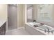 Spa-like bathroom features a garden tub, separate shower, and tiled walls with natural light from the window at 6154 Marsh Trail Dr, Odessa, FL 33556