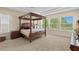Primary bedroom featuring a four-poster bed, plush carpet, and plenty of natural light at 6154 Marsh Trail Dr, Odessa, FL 33556