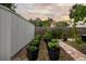 Well-maintained backyard garden featuring a row of black planters, a brick pathway, and a privacy fence at 6251 4Th S Ave, St Petersburg, FL 33707