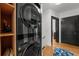 Modern black stacked washer and dryer provides space saving laundry solution near wood shelving and the home's entryway at 6251 4Th S Ave, St Petersburg, FL 33707