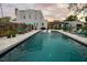 Long rectangular pool with poolside lounge chairs, a charming hammock, and elegant architectural backdrop at 6251 4Th S Ave, St Petersburg, FL 33707