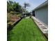 Backyard featuring artificial grass and a stone pathway along the side of the house at 6318 Ridge Crest Dr, Port Richey, FL 34668