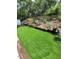 Landscaped backyard with artificial grass, garden, and a wooden retaining wall at 6318 Ridge Crest Dr, Port Richey, FL 34668