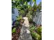 Lush backyard featuring a stone pathway lined with colorful flowers and mature trees, creating a serene outdoor space at 6318 Ridge Crest Dr, Port Richey, FL 34668