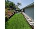 Backyard featuring artificial grass and a stone pathway along the side of the house at 6318 Ridge Crest Dr, Port Richey, FL 34668