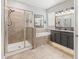 Bathroom featuring a walk-in shower, soaking tub, double vanity with dark cabinets and granite counters at 6670 Paden Wheel St, Zephyrhills, FL 33541
