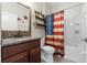 Bathroom with a framed mirror, wooden shelf, and tiled shower with patriotic curtain at 6670 Paden Wheel St, Zephyrhills, FL 33541