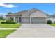 Beautiful single-story home with a manicured lawn, gray facade, and three-car garage at 6670 Paden Wheel St, Zephyrhills, FL 33541