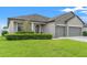 Contemporary home featuring a well-manicured lawn, gray exterior, and attached two-car garage at 6670 Paden Wheel St, Zephyrhills, FL 33541