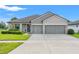 A well-maintained one-story home with a manicured lawn and three-car garage at 6670 Paden Wheel St, Zephyrhills, FL 33541