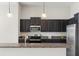 Kitchen with dark wood cabinets, stainless steel appliances, granite countertops, and stylish pendant lighting at 6670 Paden Wheel St, Zephyrhills, FL 33541