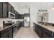 Modern kitchen featuring dark cabinets, stainless steel appliances, tile backsplash, and granite countertops at 6670 Paden Wheel St, Zephyrhills, FL 33541
