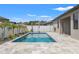 Outdoor pool with travertine pavers, umbrellas and landscaping at 6670 Paden Wheel St, Zephyrhills, FL 33541