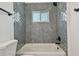 Bathroom with updated shower featuring grey tile and a white bathtub at 695 Sunset Dr, Tarpon Springs, FL 34689