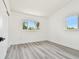 Bright bedroom features two windows, white walls, and gray wood-look flooring at 695 Sunset Dr, Tarpon Springs, FL 34689