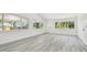 Light-filled living area featuring new grey flooring, large windows, and freshly painted walls at 695 Sunset Dr, Tarpon Springs, FL 34689