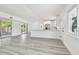 Open-concept living area featuring grey wood-look floors, ample natural light, and a modern kitchen at 695 Sunset Dr, Tarpon Springs, FL 34689