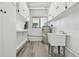 Bright laundry room with storage cabinets, laundry sink, and updated flooring at 695 Sunset Dr, Tarpon Springs, FL 34689