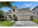 A well-maintained two-story home with a large tree, stone veneer, and a spacious driveway at 7013 Early Gold Ln, Riverview, FL 33578