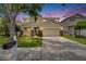 Two-story home featuring an attached two-car garage, stone accents, manicured lawn, and mature trees at 7013 Early Gold Ln, Riverview, FL 33578