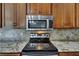 Close-up of the kitchen range with stainless steel microwave and tiled backsplash at 7013 Early Gold Ln, Riverview, FL 33578
