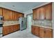 A kitchen with wood cabinets, stainless steel appliances, gray tiled backsplash, and grey vinyl flooring at 7013 Early Gold Ln, Riverview, FL 33578