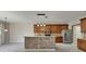 Bright kitchen with an island boasts stainless appliances, wood cabinets, and modern pendant lighting at 7013 Early Gold Ln, Riverview, FL 33578