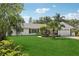 Well maintained single-story home with a lush green lawn and mature tropical landscaping at 71 Flamingo Cir, Safety Harbor, FL 34695