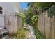Pathway through lush side yard with tropical plants and fencing on both sides at 71 Flamingo Cir, Safety Harbor, FL 34695