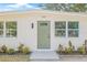 Up-close view of the home's entrance highlighting a green door, new windows, modern lighting and manicured landscaping at 7991 54Th N St, Pinellas Park, FL 33781