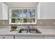 Stainless steel kitchen sink beneath a window providing natural light and peaceful outdoor views at 8175 Sturbridge # 8175, Weeki Wachee, FL 34613