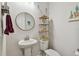 This modern bathroom has a pedestal sink, round mirror, and open shelving with charming decorations at 8192 Ivy Stark Blvd, Wesley Chapel, FL 33545